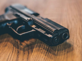 Recepimento della Direttiva armi: dalla Camera parere favorevole con osservazioni pistola in uso alla polizia tedesca su tavolo di legno