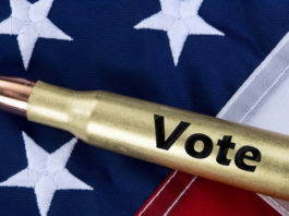 Lo studio dell’Università del Kansas sulla partecipazione politica dei proprietari di armi munizione con scritta "vote" su bandiera americana: studio sulla partecipazione politica dei proprietari di armi