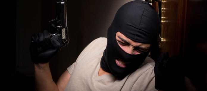 Emendamenti riforma della legittima difesa rapinatore appoggiato a una porta con pistola e passamontagna