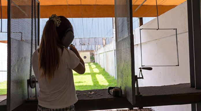 scaricare dalle tasse la donazione per impianti sportivi ragazza di spalle mentre imbraccia arma in un poligono: scaricare dalle tasse la donazione per impianti sportivi