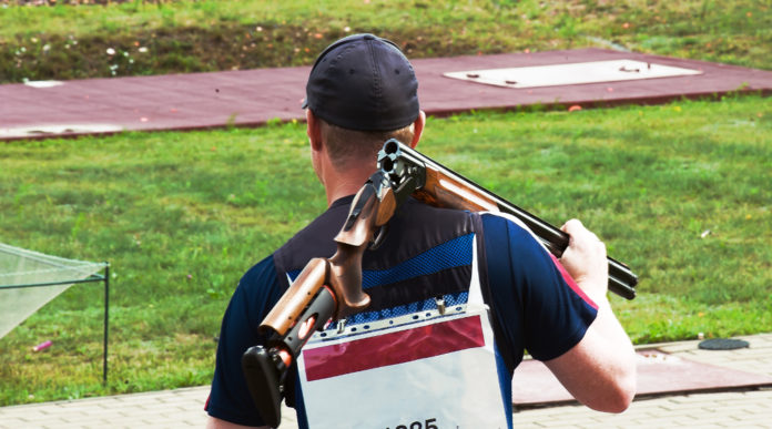 Squadre miste di tiro a volo, cinque nazioni contro l’Issf squadre miste di tiro a volo: tiratore va in posizione con fucile sulle spalle