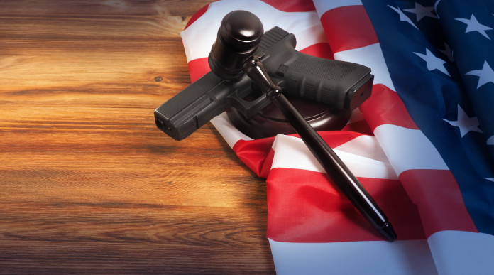 Età minima per acquistare le armi negli Stati Uniti la sentenza Età minima per acquistare le armi negli Stati Uniti: pistola con bandiera americana e martello del giudice