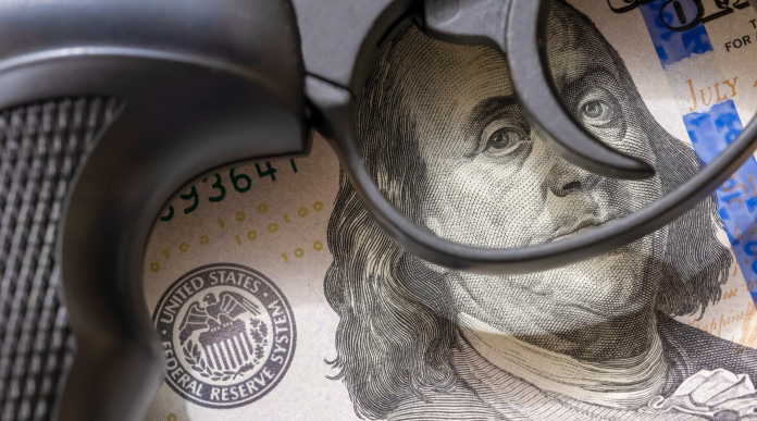 Mercato delle armi in America gli ultimi dati Mercato delle armi in America: pistola appoggiata su banconota da 100 dollari