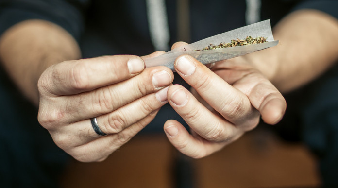 Assunzione occasionale di stupefacenti e porto d’armi, la sentenza Assunzione occasionale di stupefacenti e porto d’armi: mani di uomo preparano spinello con marijuana
