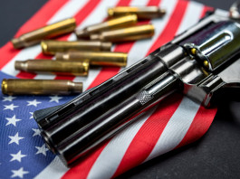 Background check negli Stati Uniti: il dato finale del 2022 Background check negli Stati Uniti: revolver a doppia canna con bandiera americana e munizioni