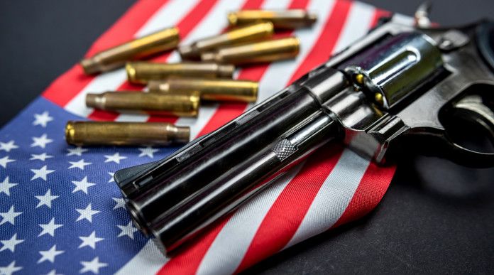 Background check negli Stati Uniti il dato finale del 2022 Background check negli Stati Uniti: revolver a doppia canna con bandiera americana e munizioni