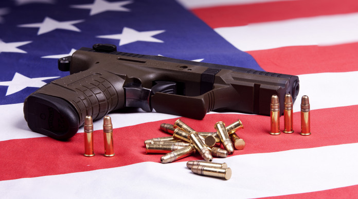 Background check in America i dati del primo trimestre Background check in America: pistola con munizioni su bandiera americana