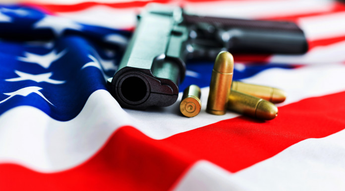 Mercato delle armi in America, la situazione a inizio dicembre Mercato delle armi in America, la situazione a inizio dicembre: pistola con proiettili su bandiera americana