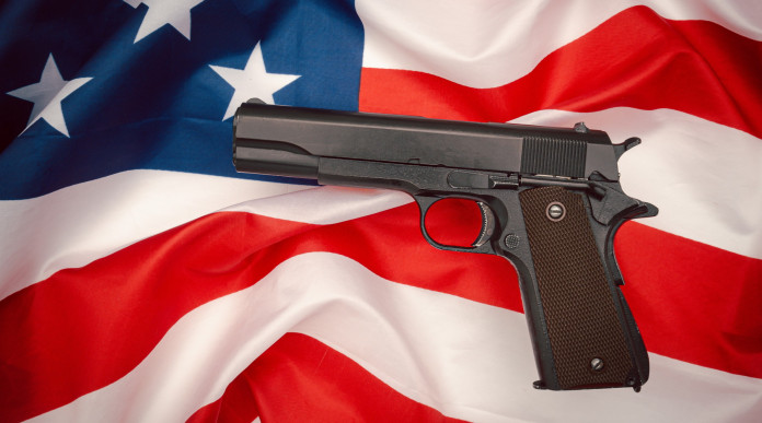 Quanti background check in America nel 2023? Quanti background check in America nel 2023? pistola semiautomatica su bandiera americana