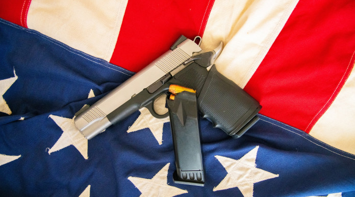 Come sta andando il mercato delle armi in America? Come sta andando il mercato delle armi in America? pistola su bandiera americana, con caricatore di scorta