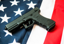 Quanti background check chiesti in America nei primi dieci mesi del 2025? Quanti background check chiesti in America nei primi dieci mesi del 2025 - pistola su bandiera americana